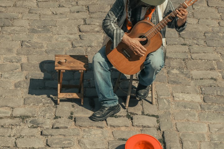 Un suonatore di strada con il suo cappello per le offerte